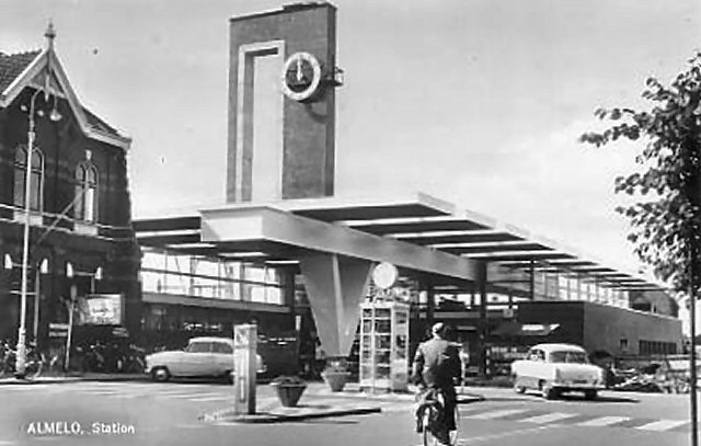 station Almelo Het oude en het nieuwe station naast elkaar. Rechts het net gereedgekomen nieuwe station, links een deel van het oude. Het torentje met het trappenhuis aan de rechterkant is al verdwenen. Door het raam kijk je dan ook in de buitenlucht.