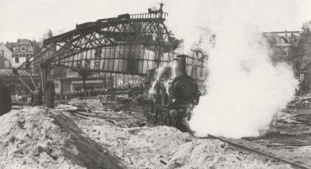 station Amsterdam Weesperpoort Afbraak van de stationskap. Die wordt onder grote belangstelling door een stoomlokomotief omvergetrokken.