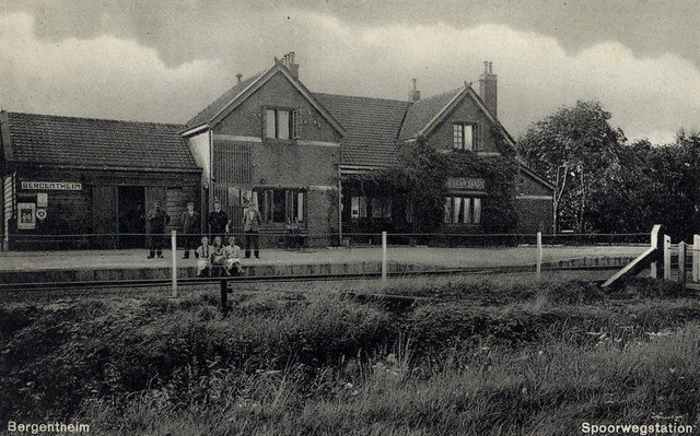 station Bergentheim Ansichtkaart perronzijde. Op het perron zijn reizigers en personeelsleden aanwezig. Aan de rechterkant is goed zichtbaar de houten goederenloods die is gebouws in 1907. In de tweede wereldoorlog is deze gebombardeerd.