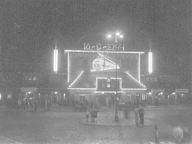 station Eindhoven Centraal Het in 1956 afgebroken stationsgebouw bij nacht. Getooid met feestverlichting voor de herdenking van de bevrijding van Eindhovenop 18-9-1944. De lichtjesroute is een traditie die elk jaar in september plaatvindt.