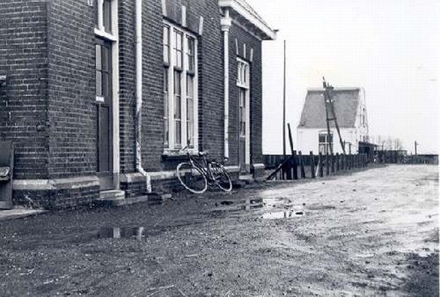 halte Legmeerpolder Straatzijde met op de achtergrond wachterswoning. Genomen tijdens de bieten campagne in het najaar van 1966. De van Hattumweg en de oprit naar het huis, waar alle wagens overheen gingen, was dan, bij regen, een laag prut die soms meer dan 6 weken bleef liggen.