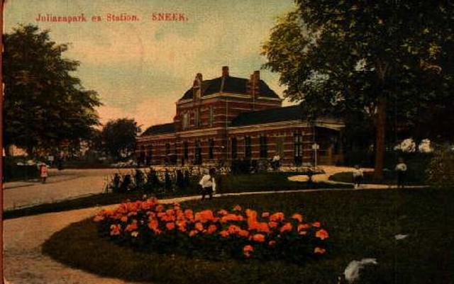 station Sneek Straatzijde. Ansichtkaart. Op voorgrond park met bloemenzee