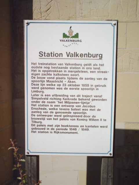 station Valkenburg Plaquette tegen de zijkant van het stationsgebouw. <p>De tekst luidt:<br><i>
<b>Station Valkenburg</b><br>
Het treinstation van Valkenburg geldt als het oudste nog bestaande station in ons land. Het is opgetrokken in mergelsteen, een streekeigen zachte klaksteen soort. De bouw vond plaats tijdens de aanleg van de spoorlijn Maastricht- Aken. Deze lijn, welke op 23 oktober 1855 in gebruik werd genomen was de eerste spoorlijn in Limburg. Later is een uitbreiding van dit traject vanaf Simpelveld richting Kerkrade bekend geworden onder de naam